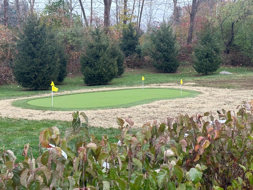 Finished putting green with flags in a landscaped outdoor setting