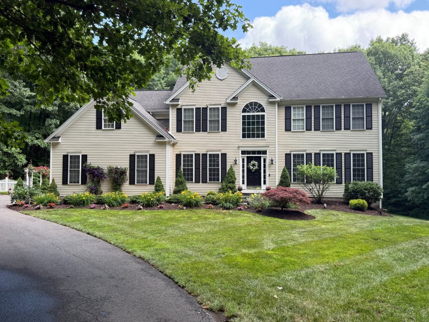 A green lawn and established planting beds surround a residential property.