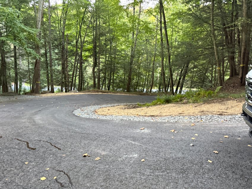Stone shoulders and prepared lawn edges follow a curved driveway.
