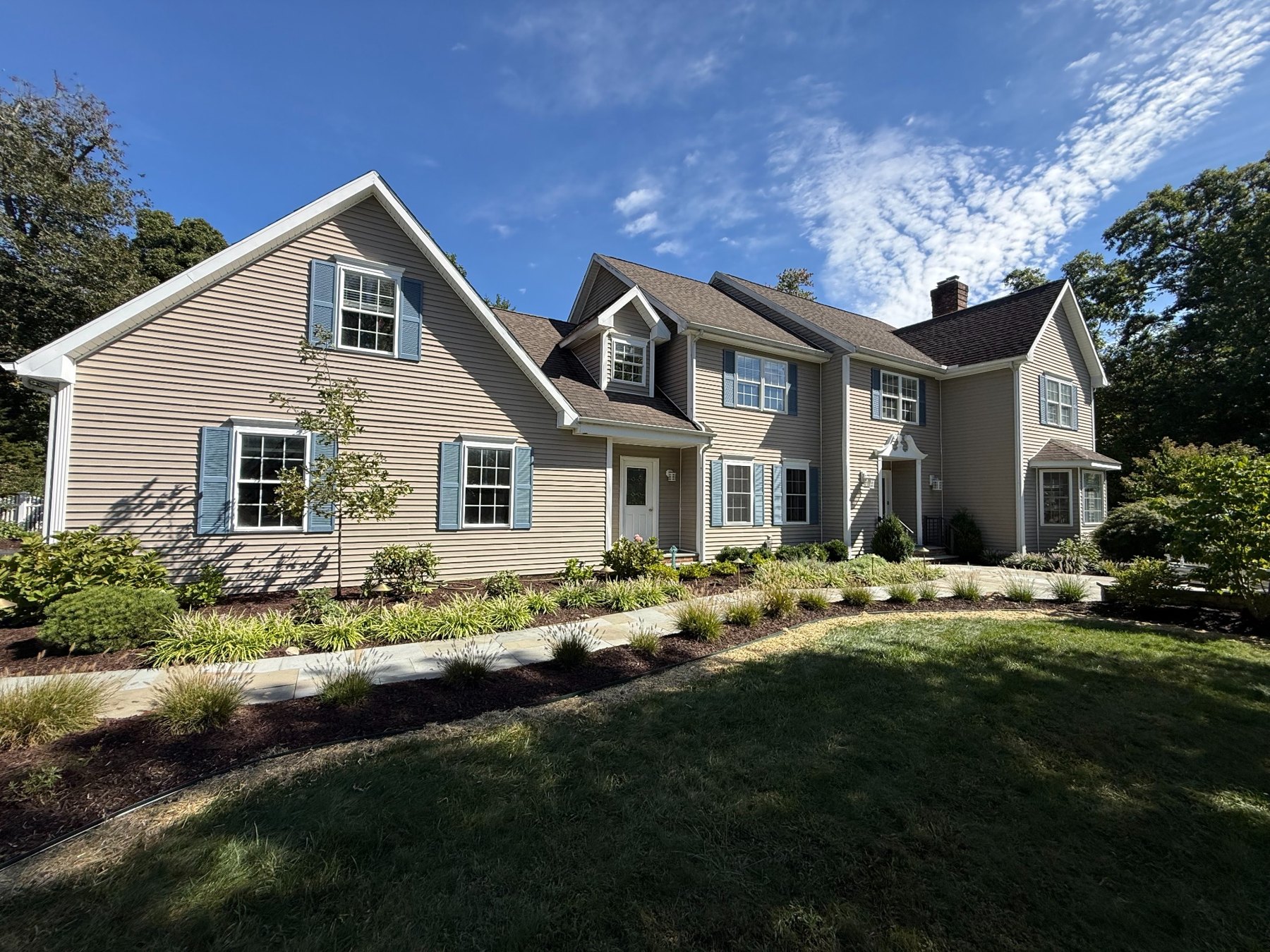 Landscaped home with mulched garden beds, curved edging and a stone walkway